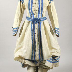 Robe princesse de promenade crème ornée de rubans en soie moirée. Fin XIXè.