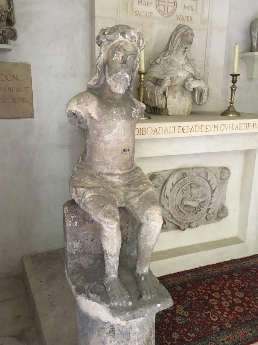Sculpture en pierre figurant un Christ assis. L’ensemble présenté sur une colonne.