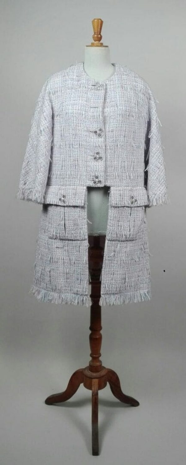 CHANEL, PARIS. Designer : Karl Lagerfeld. Manteau redingote à manches 3/4 et encolure arrondie en tweed à effet de franges dans les tons parme, rose et bleu, deux grandes poches à rabat devant, fermant sur la partie haute par des boutons en plastique transparent siglés. La doublure en soie siglée. Taille notée : 44.