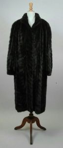 Manteau long en fourrure de vison brown travaillée en chevrons, deux poches latérales, fermant devant par des crochets.