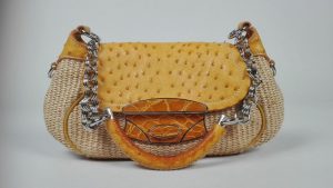 PRADA, MILANO. Sac à main à une anse porté épaule, en fibres végétales tressées et cuir d'autruche jaune, le fermoir par bouton poussoir au rabat en métal argenté et cuir façon crocodile jaune, l'anse en cuir d'autruche jaune et anneaux métalliques. L'intérieur en cuir et satin jaune avec un compartiment et une poche zippée. 30 x 15.5 x 4 cm.